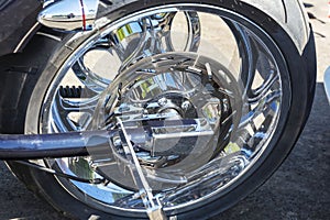 Motorcycle brake disc on the rear wheel, brake caliper and tire, shining chrome