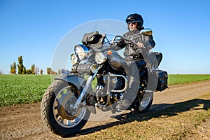 Motorcycle Driver Riding Custom Chopper Bike on Autumn Dirt Road in the Green Field. Adventure Concept.