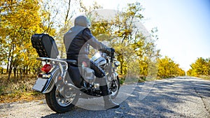 Motorcycle Driver Riding Custom Chopper Bike on Autumn Road. Travel and Adventure Concept