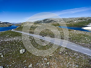 Motorcycle driving on asphalt road in Norwegian highlands. Snow road Aurlandsvegen is in Aurland, Norway