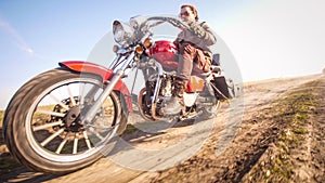 Motorcycle fast riding on dirt rural road through a field in autumn sunny day