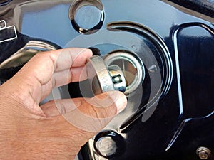 Motorcycle fuel oil tank cap in hand on cement floor background closeup