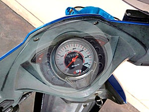 Motorcycle gauge display consist with velocity pointer and fuel oil on cement floor background closeup.