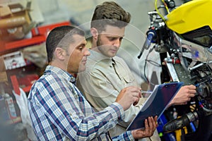 motorcycle mechanic repairing engine under supervisors guidance