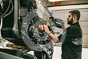 Motorcycle mechanic replacing and pouring fresh oil into engine