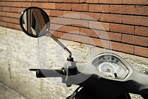 a motorcycle is parked next to a brick wall with a mirror
