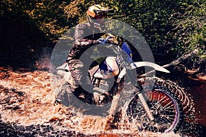 motorcycle racer on an enduro sports motorcycle crosses a river in a ford in an off-road race photo