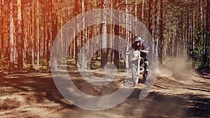 motorcycle racer on an enduro sports motorcycle rides fast on a dusty road in the forest in an off-road race photo
