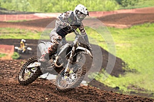 Motorcycle racer on a turn. It rained. Rider gear and motorcycle in the dirt