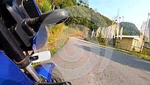 Motorcycle ridding from low angle at twisty mountain road with lush green forests