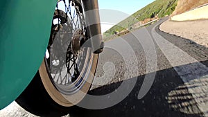 Motorcycle ride on a winding coastal road seen from the front wheel. Sardinia