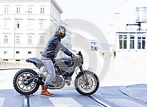 Motorcycle rider on custom made scrambler style cafe racer in th