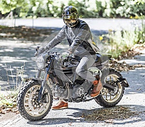 Motorcycle rider on custom made scrambler style cafe racer in th photo