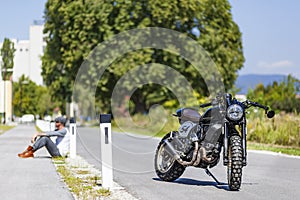 Motorcycle rider sitting near custom made scrambler style cafe r