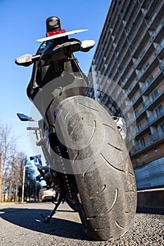 Motorcycle standing on stand on an urban street. City roadside, nobody, wide angle rear view