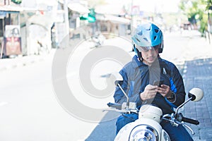 Motorcycle taxi driver texting on mobilephone on the side of the