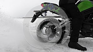 Motorcycle wheel is slipping on snow stucking in snowdrift in motocross closeup.