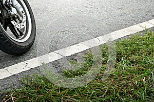 Motorcycle wheels are on the road and grass background,soft sunlight,car wheels and traffic lines on the road,car braking system,