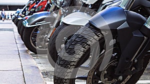Motorcycles parked on the motorcycles parking lot on the street. Closeup view of motorcycles front wheels