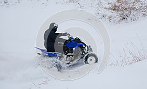 A motorcyclist on an ATV rides off-road in a snowy winter forest