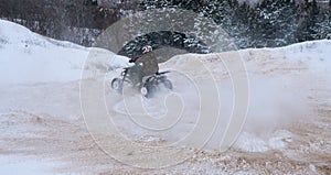A motorcyclist on an ATV rides off-road in a snowy winter forest