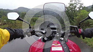 Motorcyclist on Bike Rides on a Landscape Mountain Road in the Rain