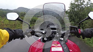 Motorcyclist on Bike Rides on a Landscape Mountain Road in the Rain