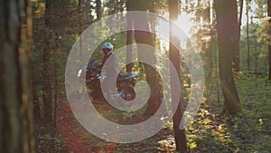 Motorcyclist biker rides slowly through the forest on a motorcycle. Forest path. Preparing for a bike trip. At sunset in