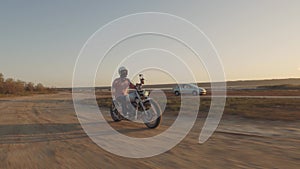 Motorcyclist driving his motorbike on the dirt road during sunset 4k shot