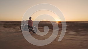 Motorcyclist driving his motorbike on the dirt road during sunset 4k shot