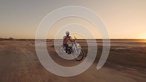 Motorcyclist driving his motorbike on the dirt road during sunset 4k shot