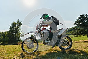 A motorcyclist equipped with professional gear, rides motocross on perilous meadows, training for an upcoming
