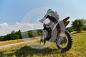 A motorcyclist equipped with professional gear, rides motocross on perilous meadows, training for an upcoming