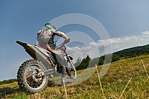 A motorcyclist equipped with professional gear, rides motocross on perilous meadows, training for an upcoming