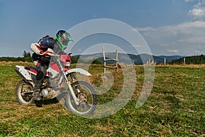 A motorcyclist equipped with professional gear, rides motocross on perilous meadows, training for an upcoming