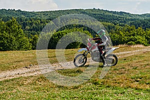 A motorcyclist equipped with professional gear, rides motocross on perilous meadows, training for an upcoming