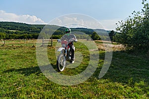 A motorcyclist equipped with professional gear, rides motocross on perilous meadows, training for an upcoming