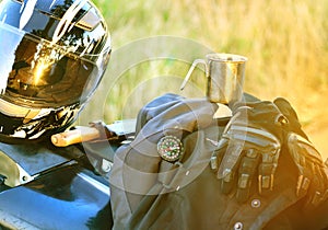 Motorcyclist helmet, gloves, knife, compass and other accessories lie on the seat of a motorcycle.