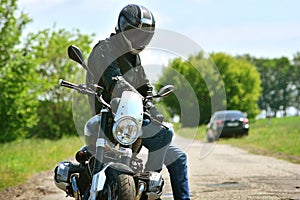 Motorcyclist in helmet and leather jacket sits on his motorcycle