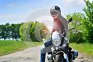 Motorcyclist in helmet and leather jacket sits on his motorcycle outdoors.