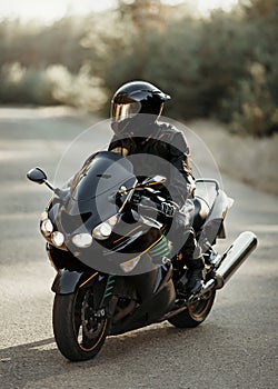 Motorcyclist in a helmet on a motorcycle on a country road. Guy driving a bike during a trip. Riding a modern sports motorcycle on