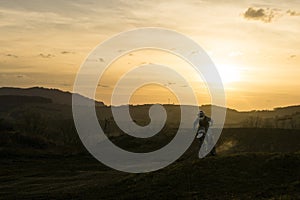 Motorkár skákajúci na motorke počas farebného východu alebo západu slnka.