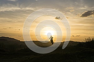 Motorcyclist jumping on his motorcycle during the colorful sunrise or sunset.