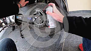 Motorcyclist Lubricates a Motorcycle Chain using a Spray Can. First-person view