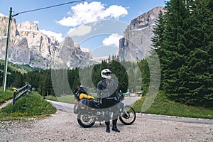 Motorcyclist man standing with adventure motorbike on the mountain road, beautiful summer view, danger road in mountains, freedom