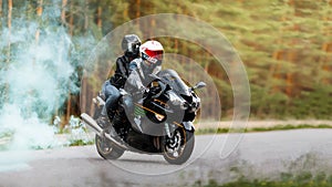 Motorcyclist in protective gear and helmet sitting with a girl on a sports motorcycle on a blurred background with smoke, copy photo