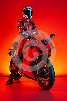 Motorcyclist in red gear posing with sports bike photo