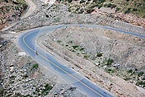 Motorcyclist rides along a winding mountain road, passing through an expansive canyon