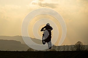 Motocyklista jazdiaci mimo cesty pri západe slnka. Slovensko