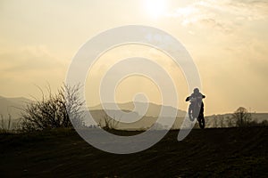 Motocyklista na koni mimo silnici při západu slunce. Slovensko